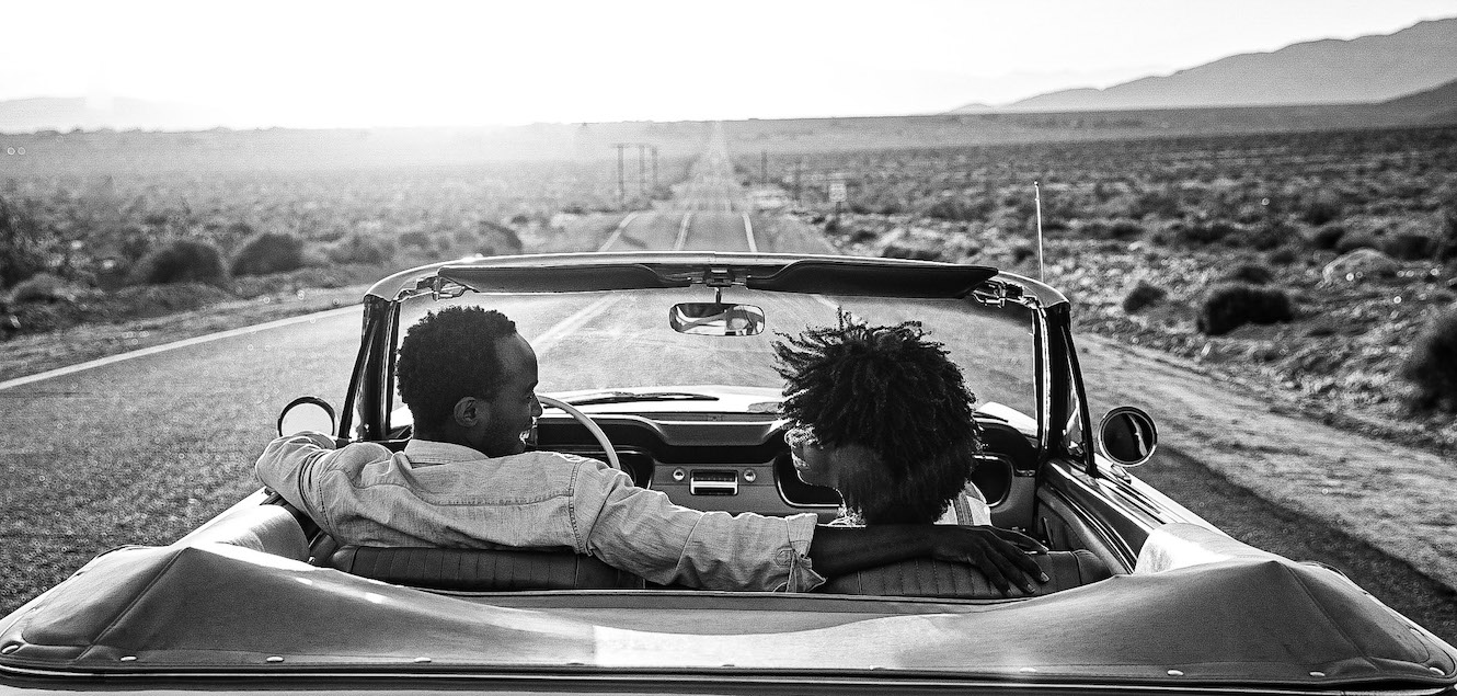 Couple driving down a desert road.